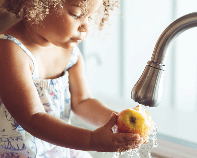 Young girl washing an apple.